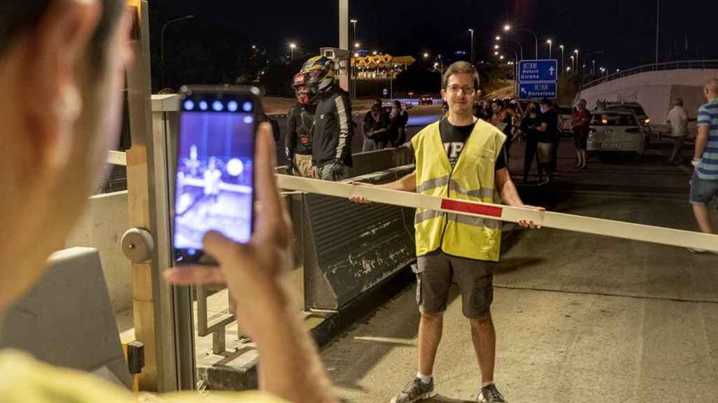 Un hombre sostiene la valla arrancada de un peaje en la C-32 / CG (Lena Prieto)