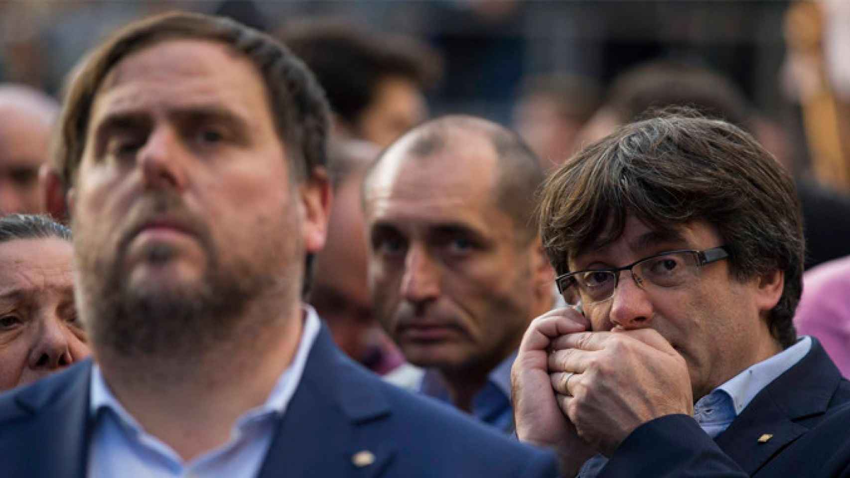 Carles Puigdemont, expresidente catalán, habla discretamente por el móvil detrás de Oriol Junqueras (ERC) / EFE