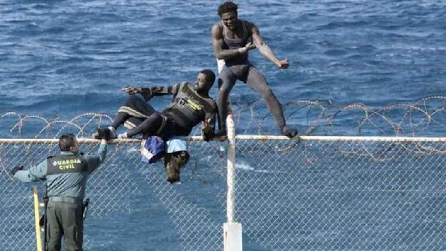 Varios inmigrantes permanecen encaramados a una valla fronteriza de Ceuta en una imagen de archivo