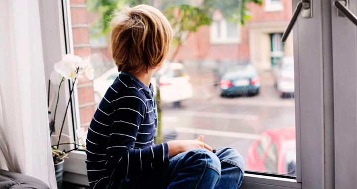 Un niño poco comunicativo mira por la ventana / PEXELS