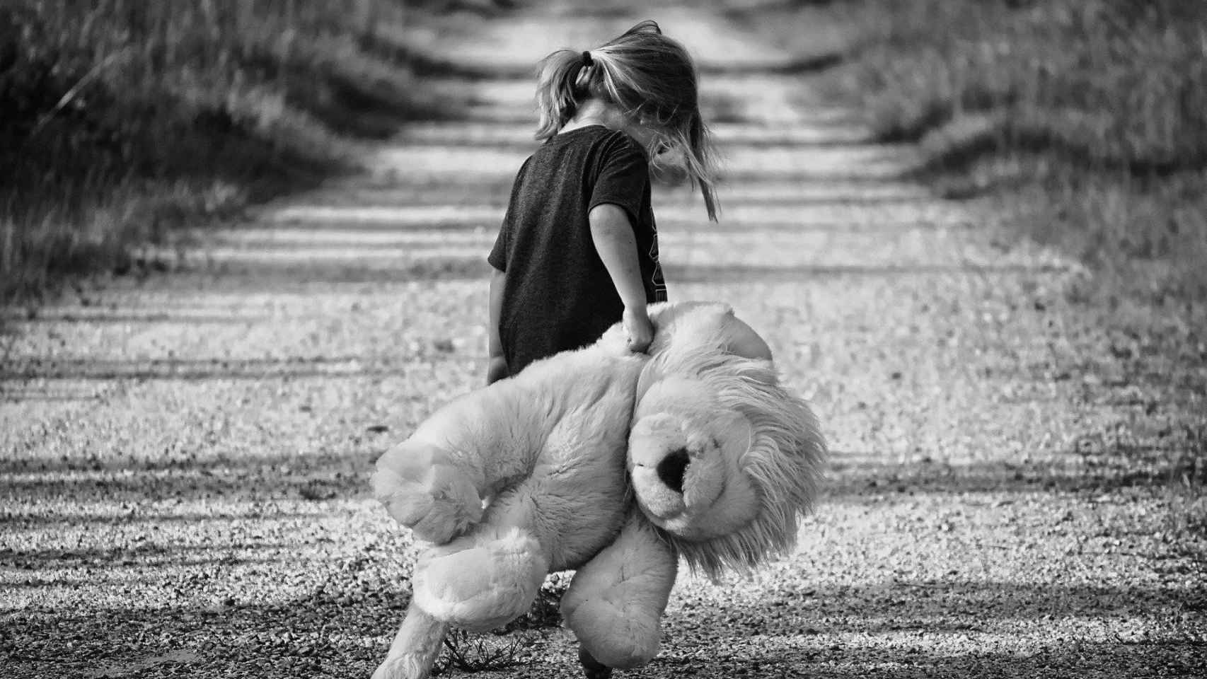 Una niña pasea por un camino arrastrando su peluche / CG