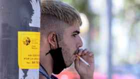 Un joven con la mascarilla bajada para poder fumar / EP