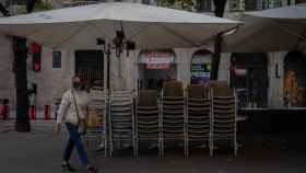 Una mujer pasea ante una terraza cerrada a causa de las restricciones: el Gremio de restauración pide una reducción de las tasas  / EP