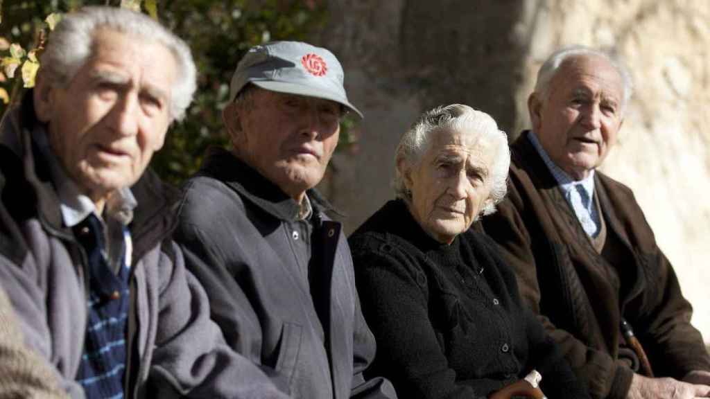 Cuatro jubilados sentados en un banco que cobran pensión