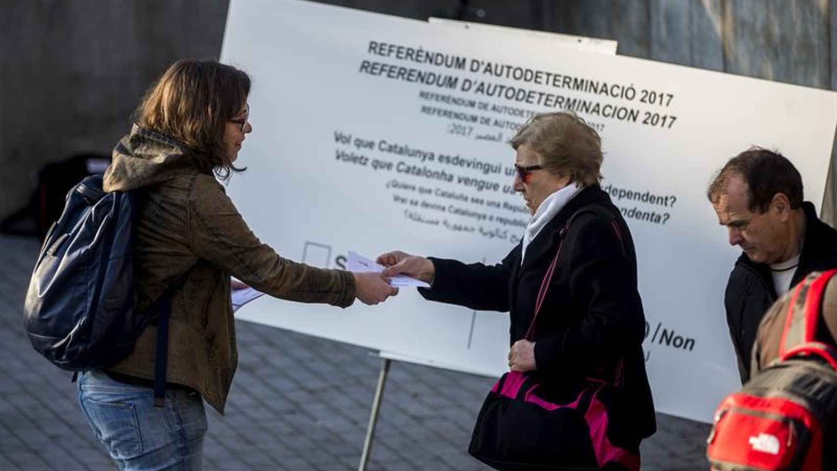 La diputada de la CUP, Eulàlia Reguant (c), reparte papeletas en el centro de Barcelona en el marco de una campaña en que la CUP ha repartido en diferentes puntos de Cataluña 250.000 papeletas con su propuesta de pregunta para un eventual referéndum de in