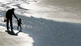 Un abuelo pasea por la playa con su nieto. Niños / EFE