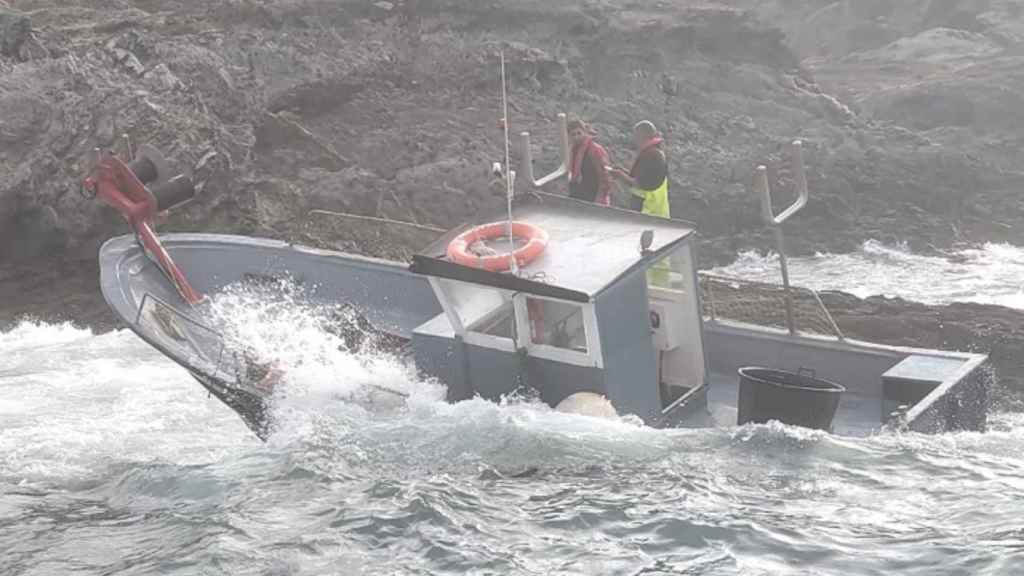 Los dos pescadores, refugiados en las rocas, tras naufragar su embarcación en Girona / SALVAMENTO MARÍTIMO