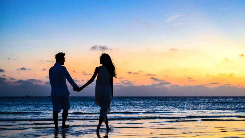 Pareja en la playa al atardecer / PEXELS