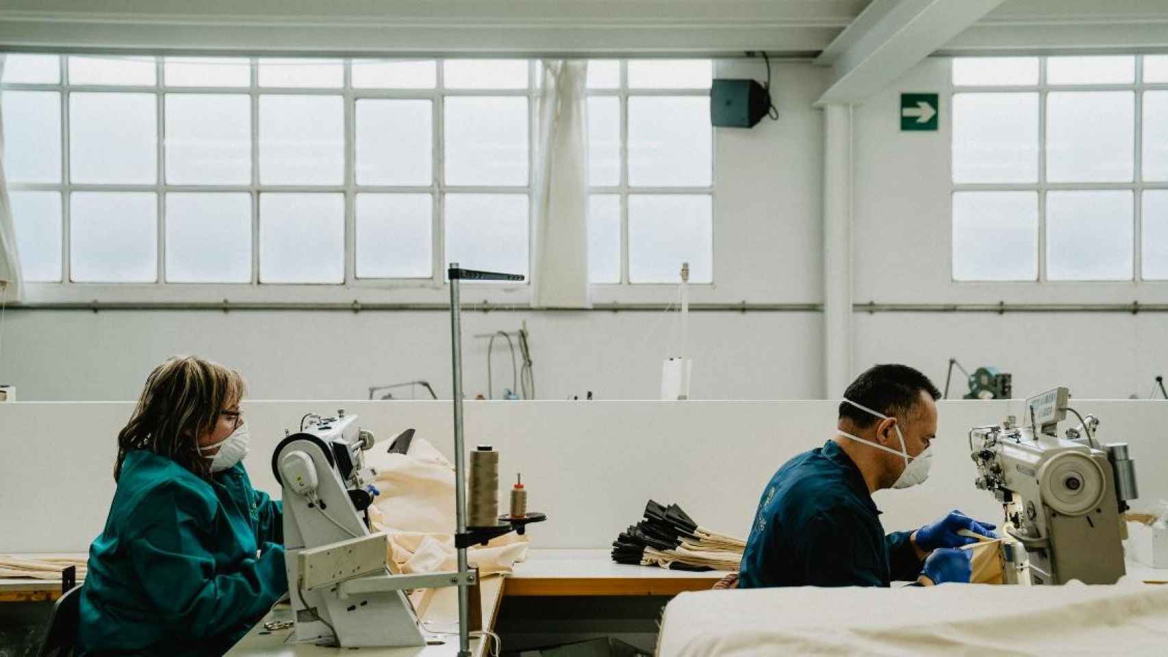 Empleados de una fábrica en sus puestos de trabajo, cosiendo material sanitario / EP