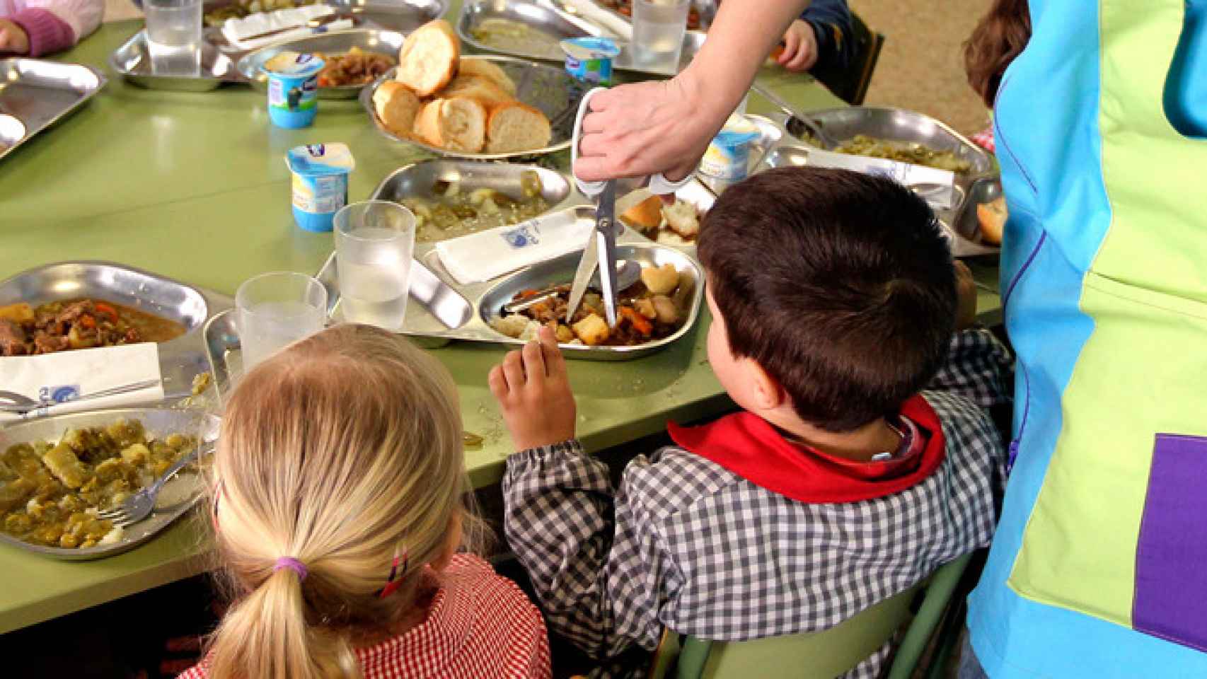 Dos alumnos de preescolar en el comedor de un colegio junto a una monitora / EFE