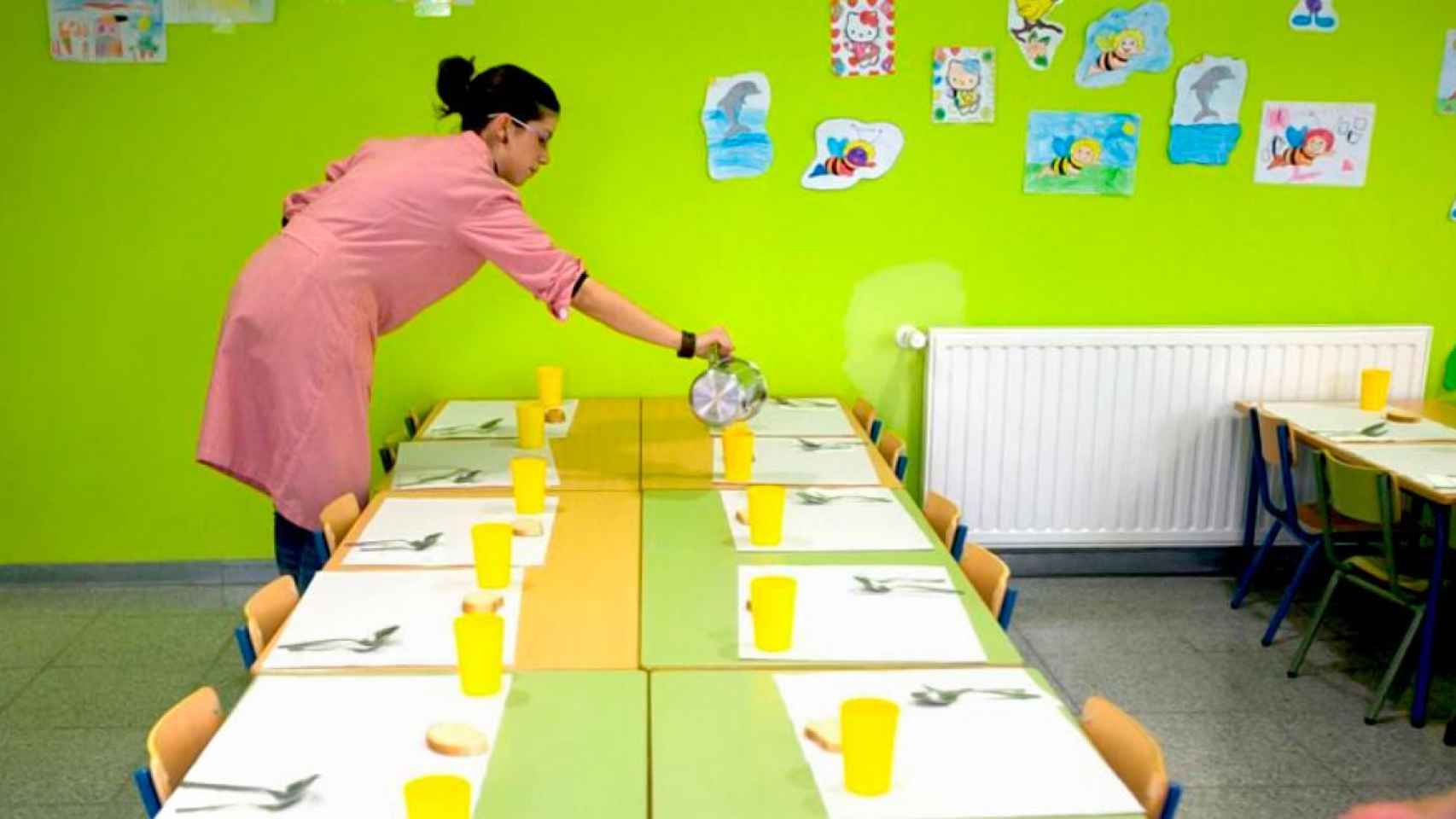 Una mujer sirve la bebida para los niños en un comedor escolar / EP