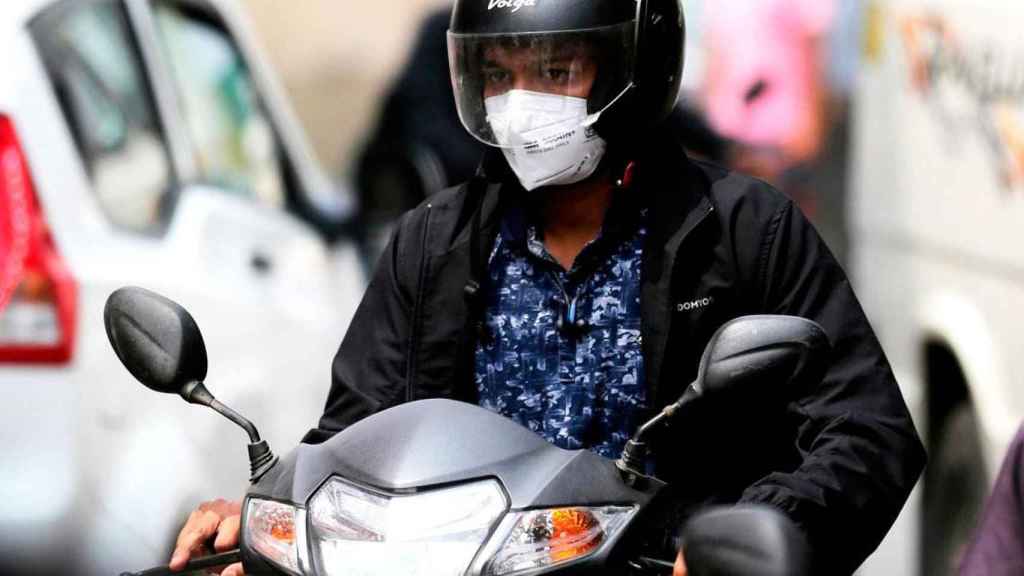 Imagen de una usuaria de moto con mascarilla protectora contra el virus / EFE