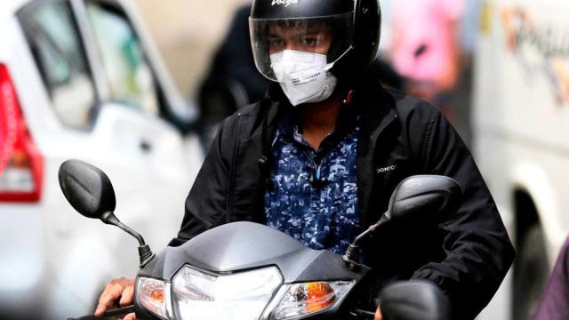 Imagen de una usuaria de moto con mascarilla protectora contra el virus / EFE