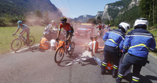 El ciclista Luis León Sánchez pasa junto a manifestantes sentados en la carretera mientras la policía intenta desalojarlos durante la 10ª etapa del Tour de Francia 2022 / EFE
