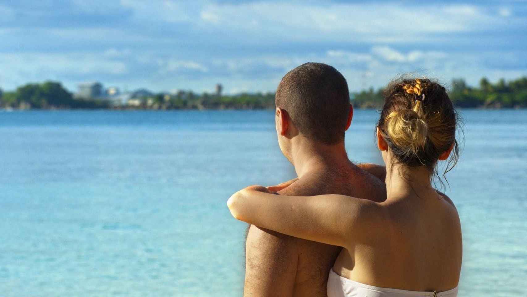 Una pareja en la playa en sus vacaciones de verano / CG