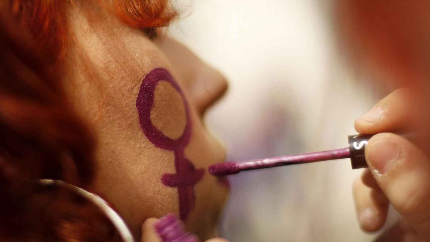 Una mujer siendo maquillada antes de manifestarse / EFE