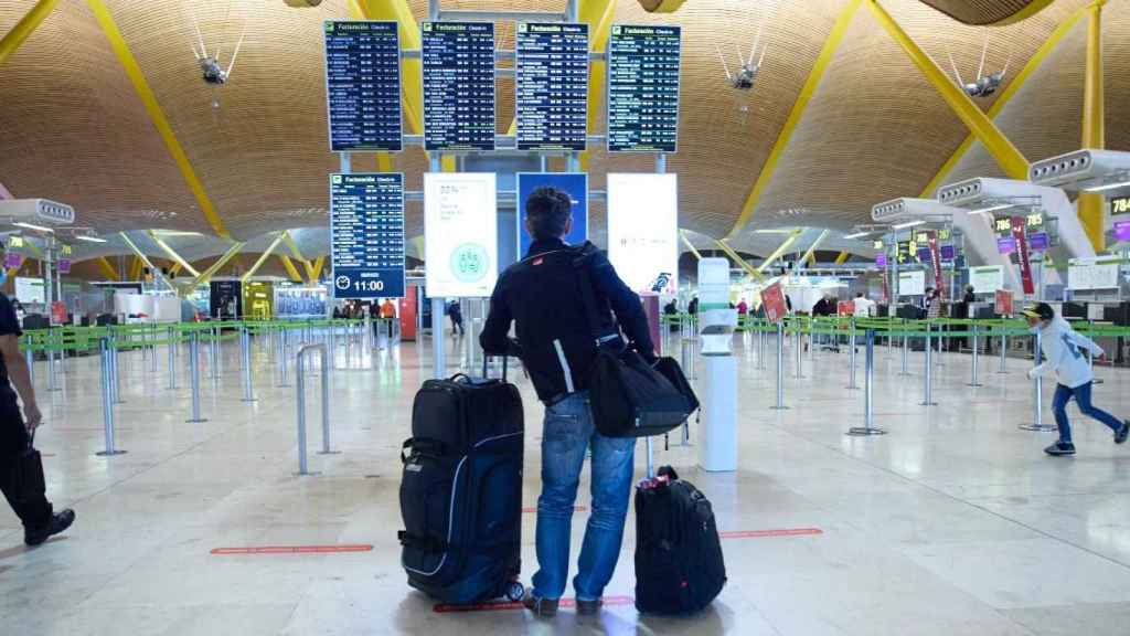 Un hombre espera frente a las pantallas de la T4 de Barajas