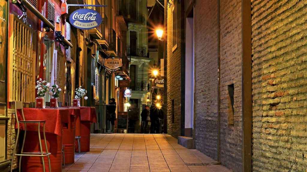 Vista nocturna de una calle con varios locales y tabernas / CG