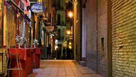 Vista nocturna de una calle con varios locales y tabernas / CG