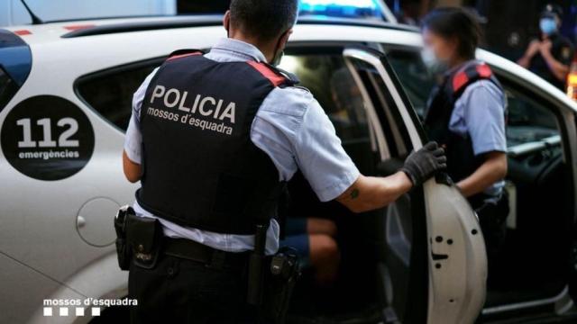 Agentes de Mossos meten a una persona detenida en el coche para trasladarla a comisaría / MOSSOS