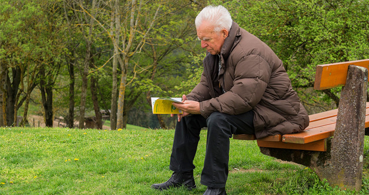 Un anciano lee un libro en el parque / PIXABAY