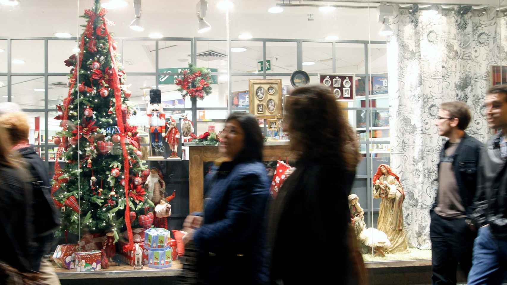 Varios viandantes pasan por delante de un escaparate en Navidad / EFE