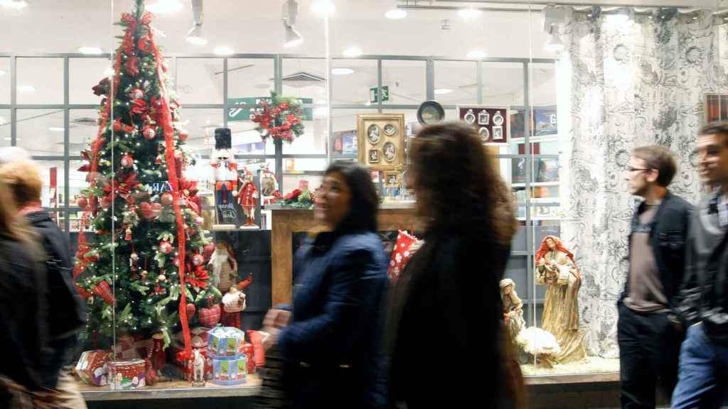 Varios viandantes pasan por delante de un escaparate en Navidad / EFE