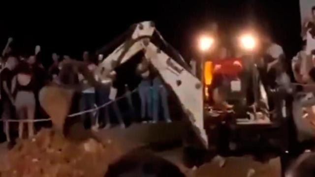 Un participante del macrobotellón de la UAB se monta en una excavadora