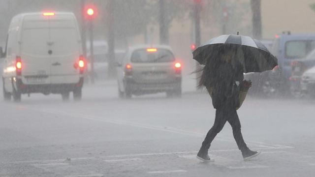 Una persona cruza la calle entre las lluvias, en imagen de archivo / EFE