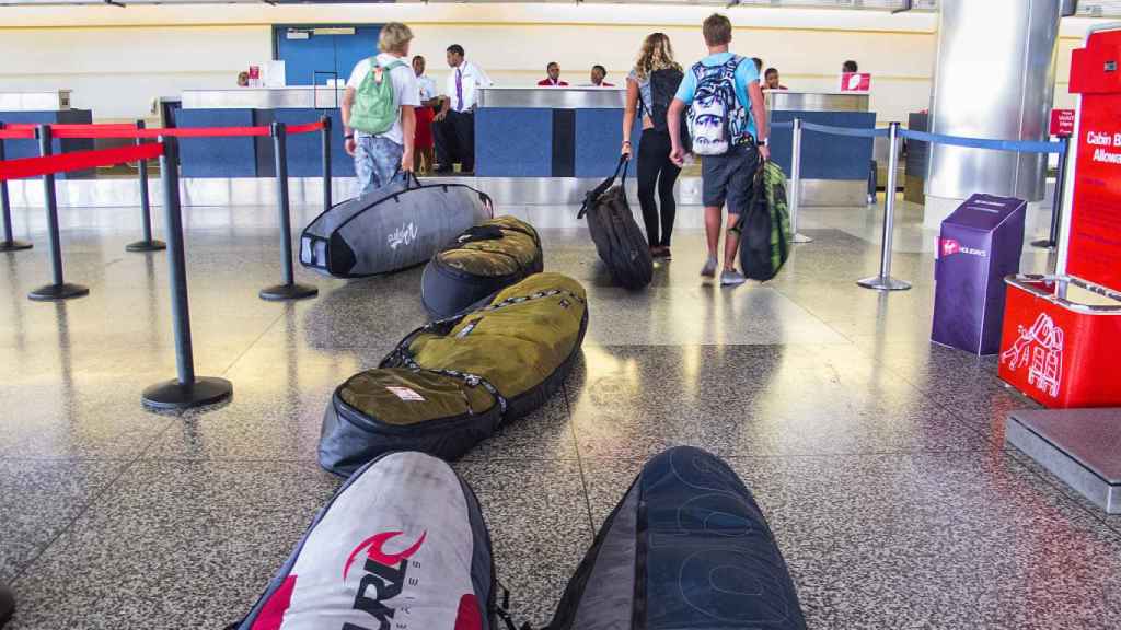 Pasajeros con tabla de surf en un aeropuerto.