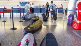 Pasajeros con tabla de surf en un aeropuerto.