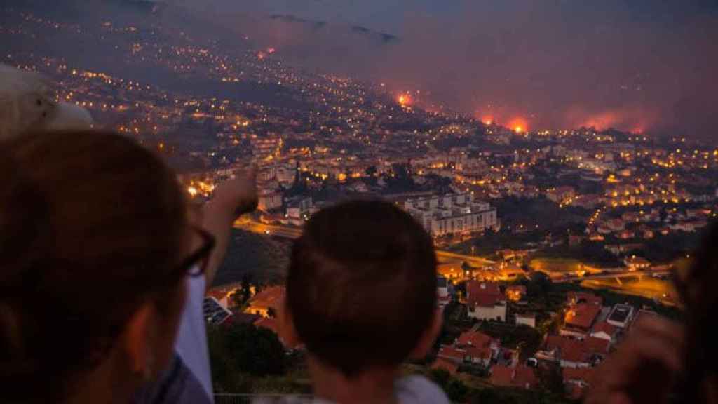 Dos vecinos observan el avance del fuego en Madeira (Portugal) el martes por la noche. / EFE