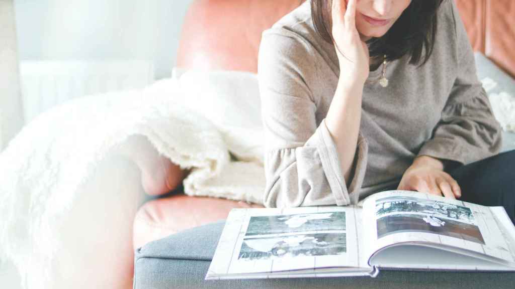 Mujer hojeando un álbum de fotos PEXELS