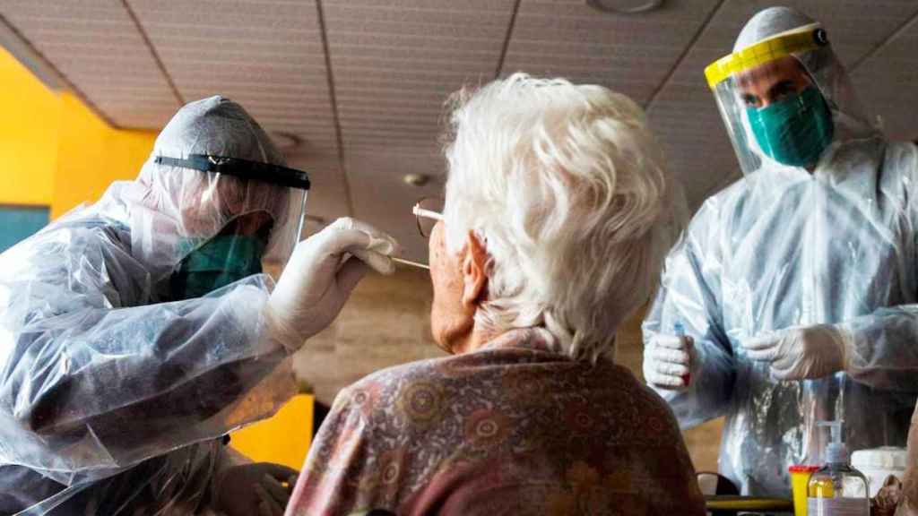 Imagen de dos sanitarios cogiendo muestras a una persona mayor para un test PCR contra el virus / CG