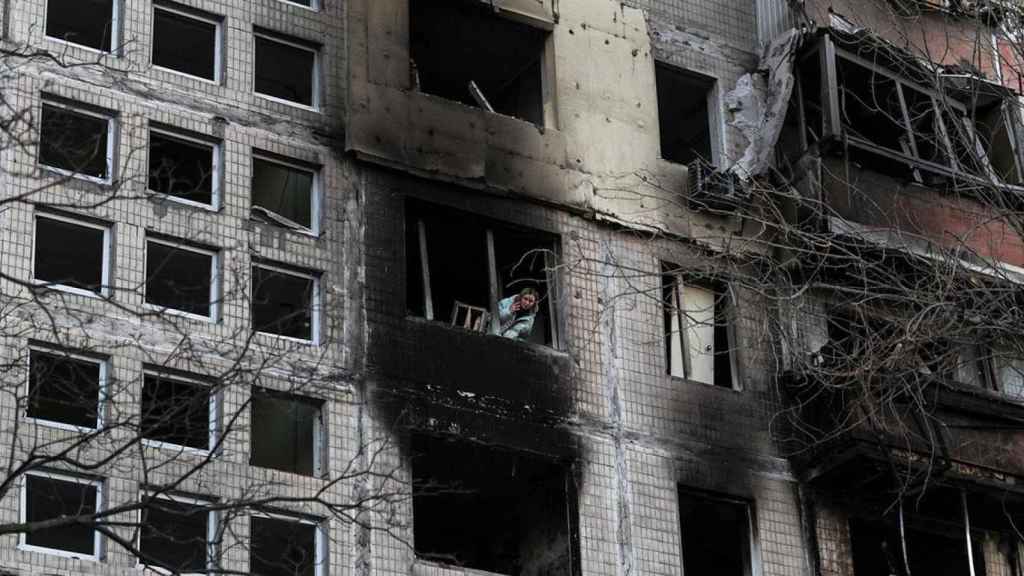 Una mujer se asoma a la ventana de un edificio destruido por un bombardeo ruso en la capital de Ucrania / Miguel A. Lopes (EFE)