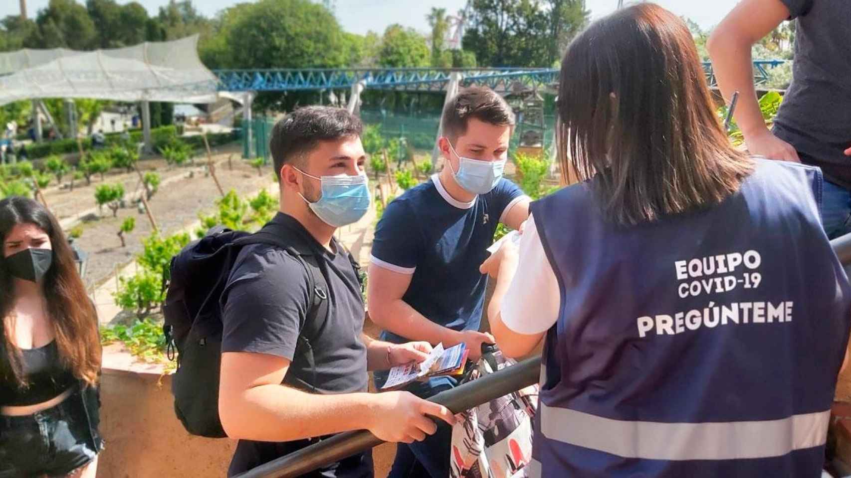 Una informadora contra el Covid-19 atiende a visitantes en la cola de la atracción Furius Baco / CG