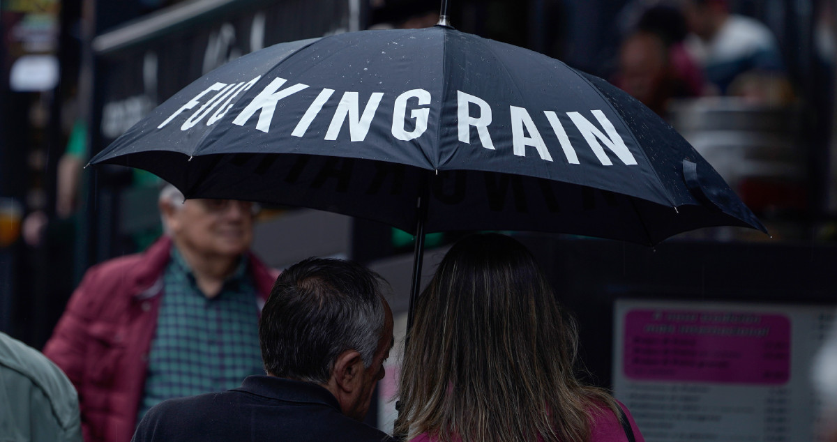 Una pareja se protege de la lluvia con un paraguas en la calle / EFE Paco Paredes