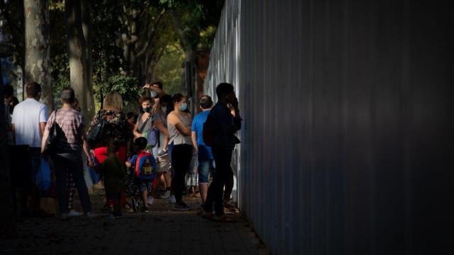 Padres y escolares esperan a las puertas de un colegio / EP