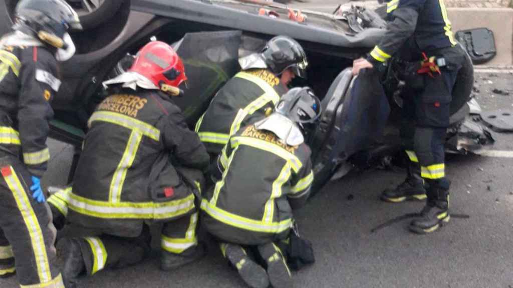 Los bomberos rescatan a uno de los heridos tras volcar el coche en el que viajaban / BOMBERS