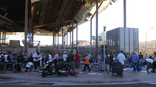 Un grupo de los nuevos 'manteros' vende sus productos en la puerta de Los Encantes de Barcelona./ CG