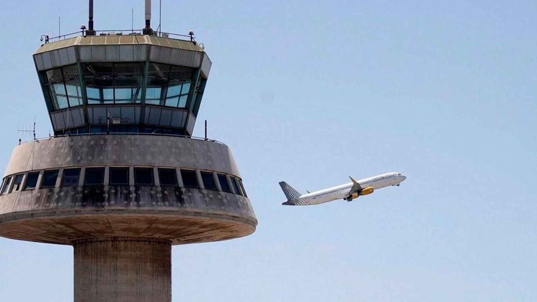 Un avión despega ante la torre de control del aeropuerto El Prat