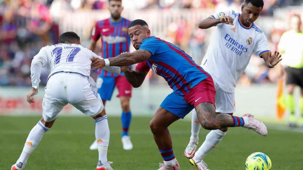 Memphis Depay disputa un balón con dos jugadores del Real Madrid en el clásico de la Liga / EFE