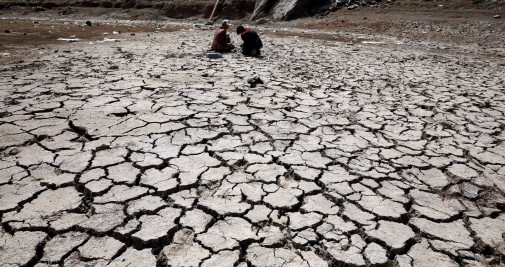 Personas sentadas en el lecho de un embalse afectado por la sequía en las afueras de Saná (Yemen) - EFE/ Yahya Arhab