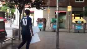 Fotografía en la que se aprecia a uno de los jóvenes con carteles de Junts per Catalunya arrancados de las farolas / CG