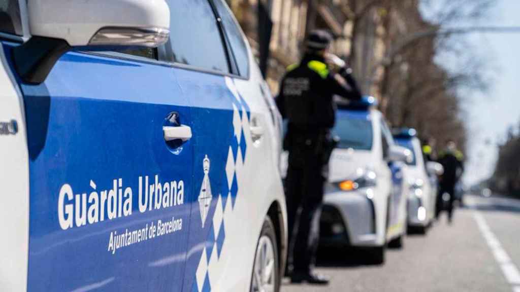 Un agente de la Guardia Urbana de Barcelona junto a un coche patrulla / GUARDIA URBANA