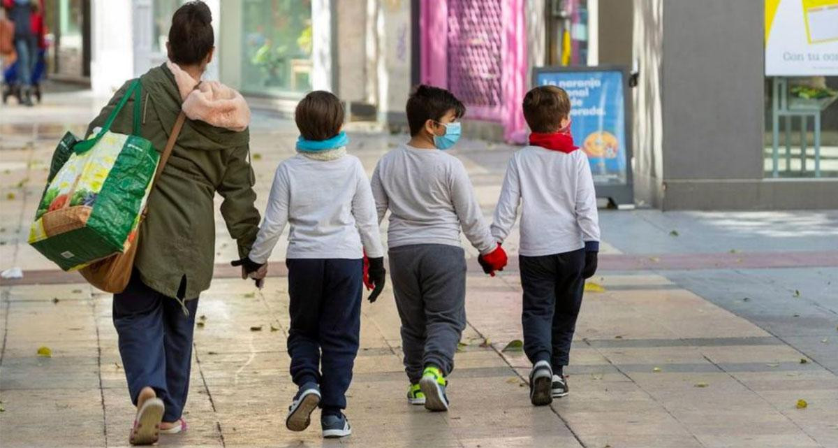 Una mujer pasea con tres niños con mascarillas / EFE