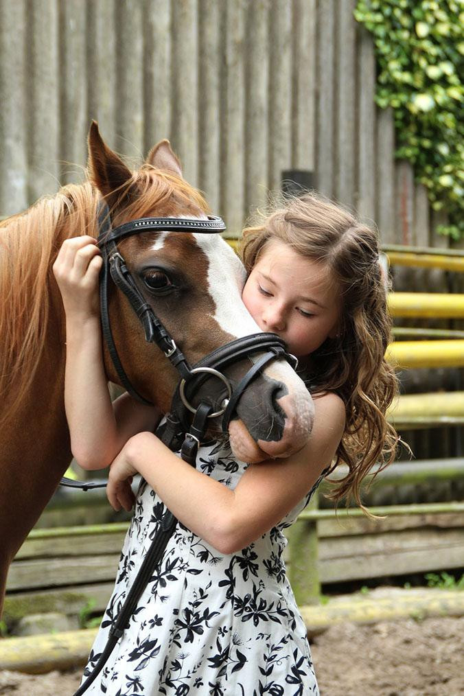 Niña acariciando a un poni / PIXABAY