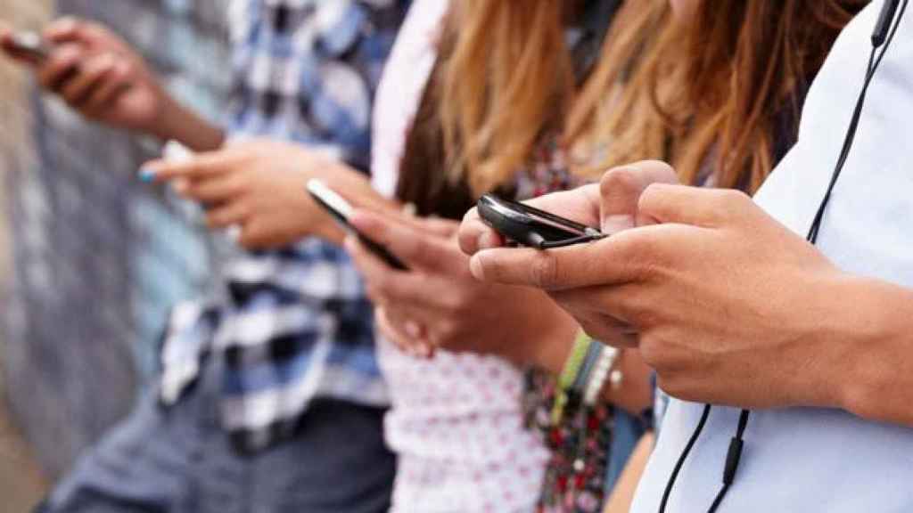 Un grupo de adolescentes mirando sus teléfonos móviles / CG