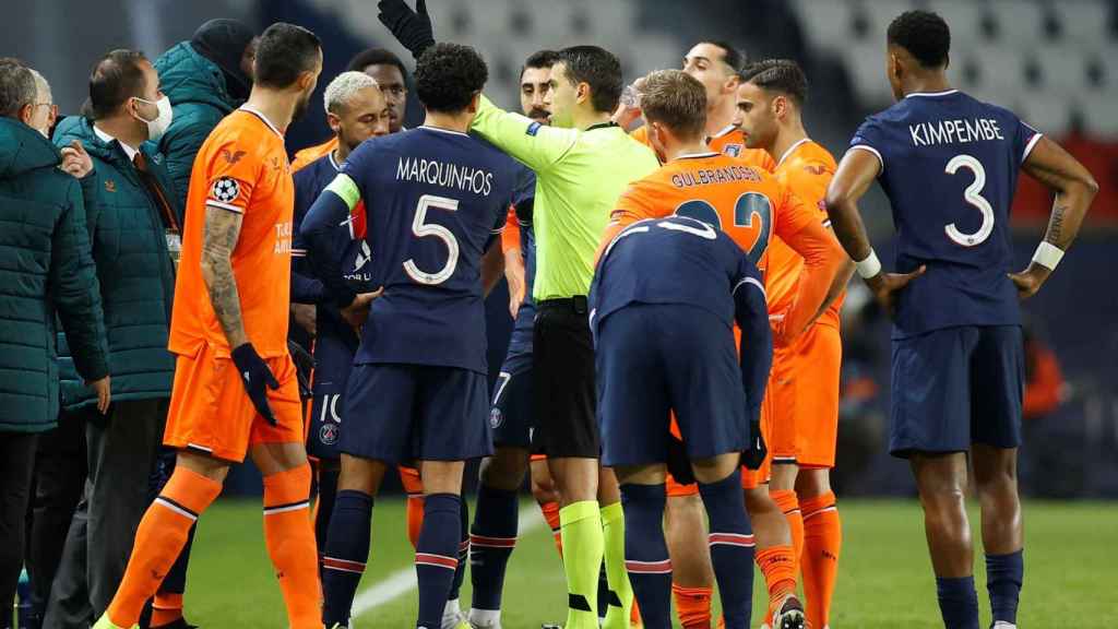 Los jugadores del PSG y del Basaksehir pidendo explicaciones a Sebastian Colescu / EFE