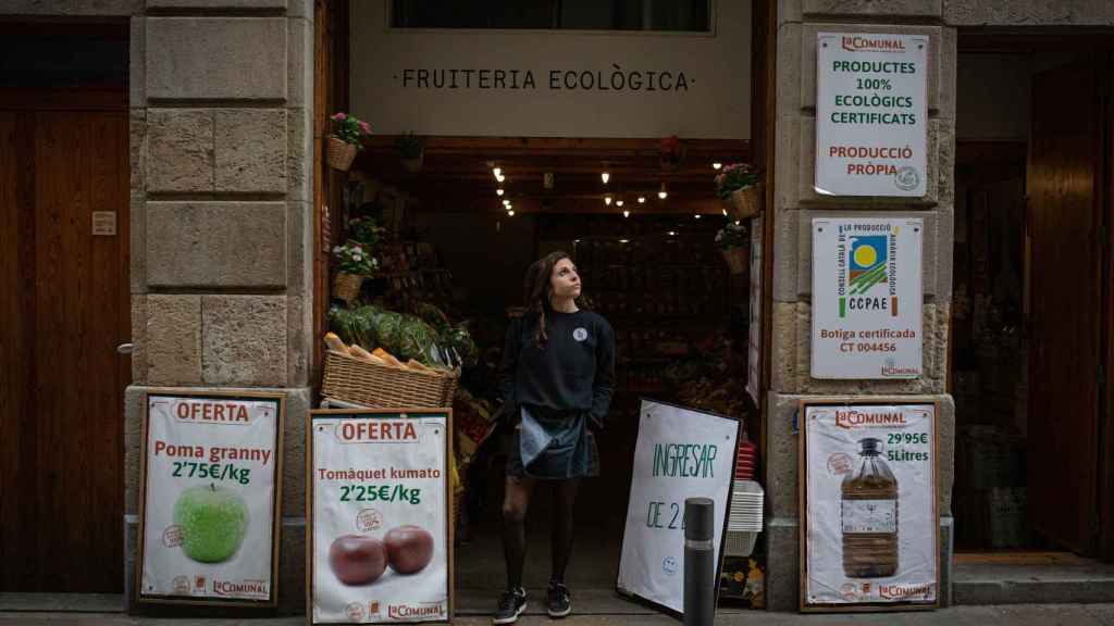 PIB. Una mujer, en la puerta de su frutería, uno de los comercios esenciales / EFE